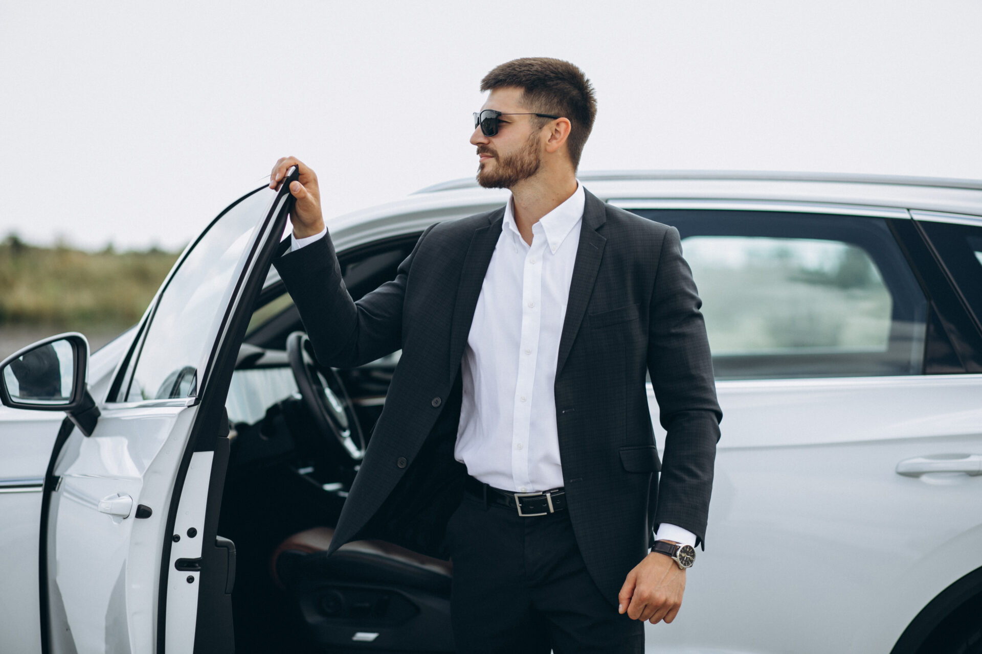 Handsome business man by the white car